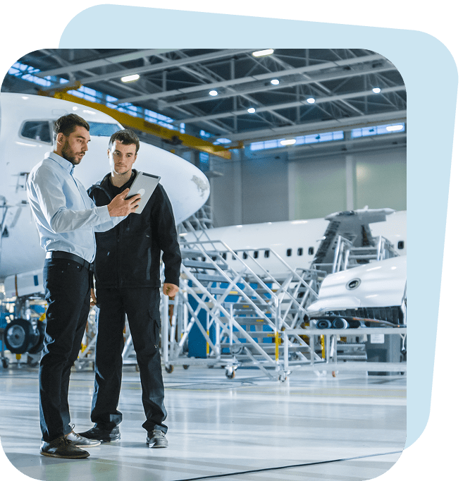 Two men discussing inside airplane hangar.