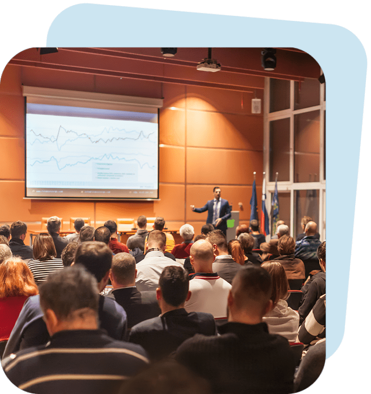 Audience attending a presentation with graph displayed.