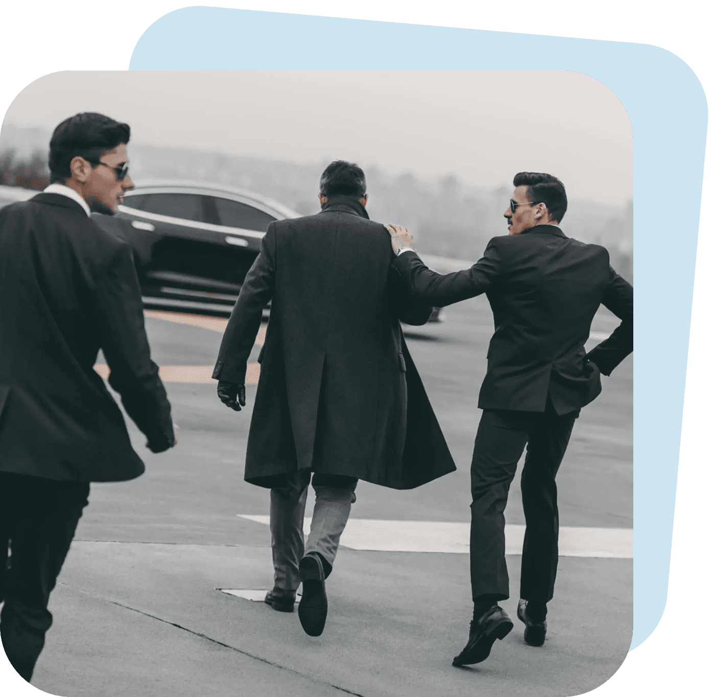 Three men in suits walking towards a car on a road.