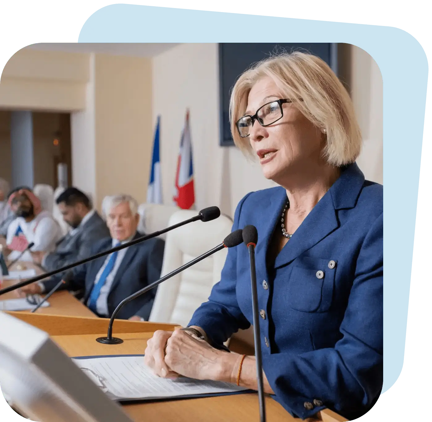 Woman speaking at a formal conference podium with an audience.